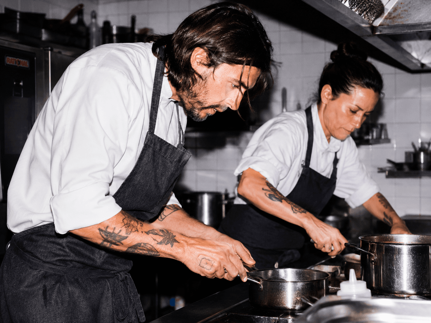 Cocineros trabajando coordinados en una cocina profesional limpia